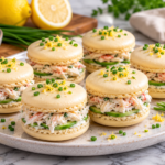Macarons salés au crabe et citron garnis de fromage frais, chair de crabe et ciboulette, présentés dans une assiette blanche